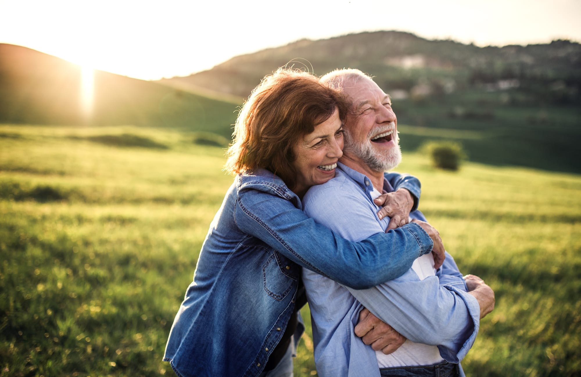 Senior couple laughing together outdoors at sunset